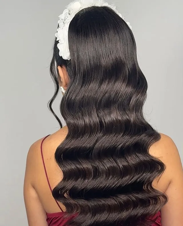 Coafură de eveniment cu valuri Hollywood pe păr brunet, cu accesoriu floral