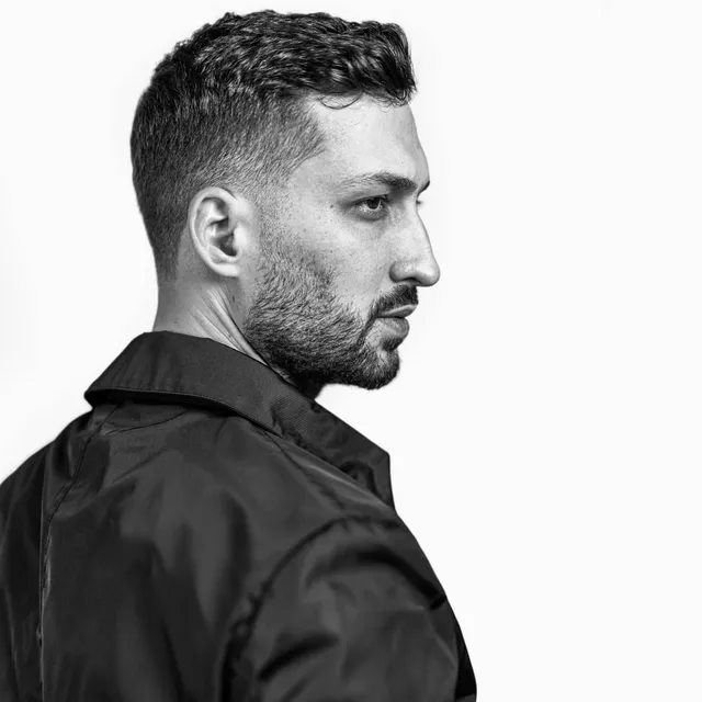 Portret de studio alb-negru, tuns fade cu barbă, profil