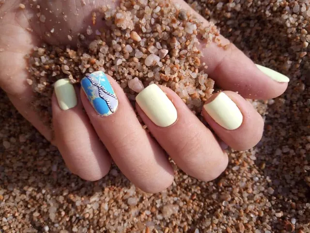 Manichiură galben pastel cu accent floral albastru, inspirație de vară