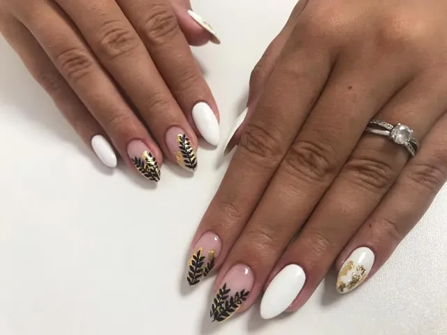 Manichiură albă cu model floral negru și auriu, formă migdală